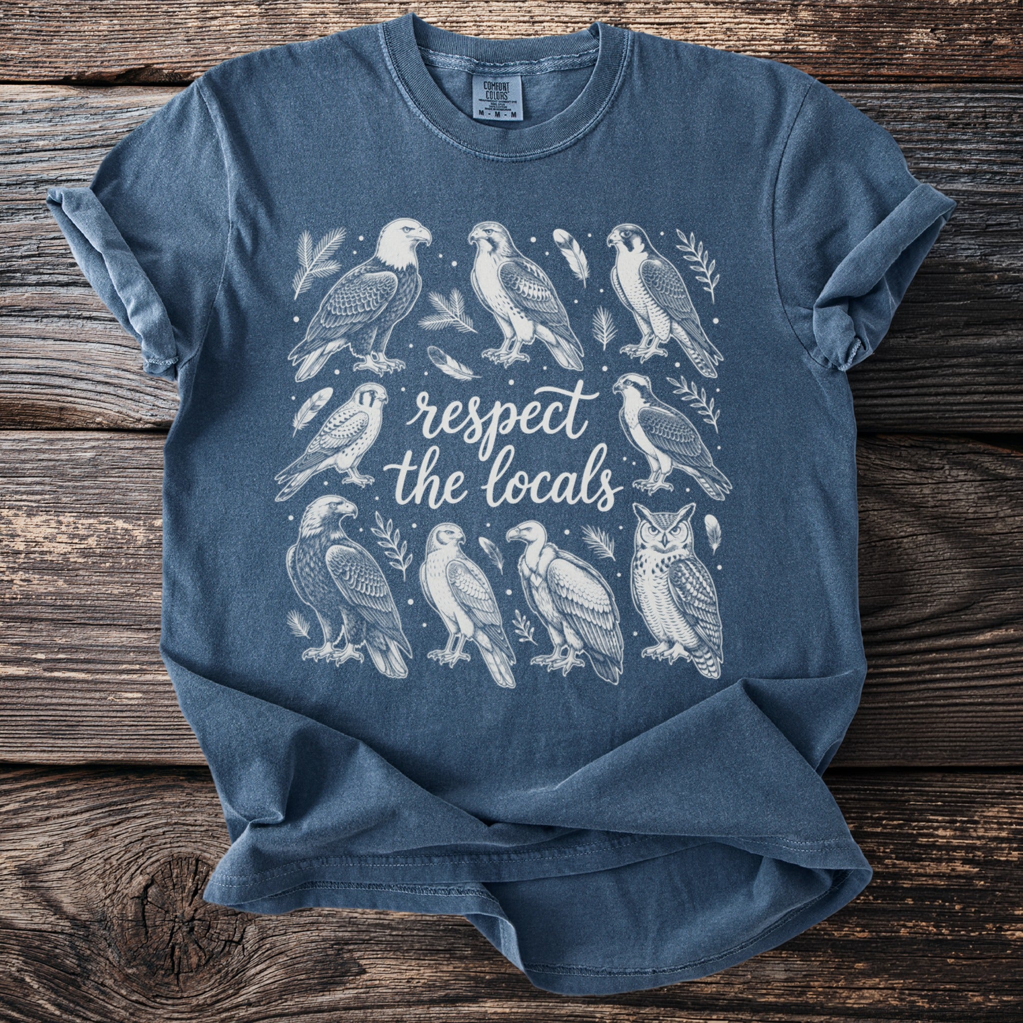 Blue t-shirt with white illustration of birds and the text "respect the locals."
