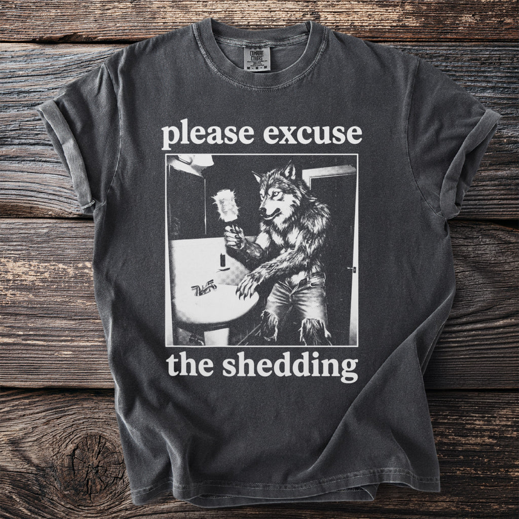 Dark grey t-shirt with a werewolf at a sink and the text "please excuse the shedding."