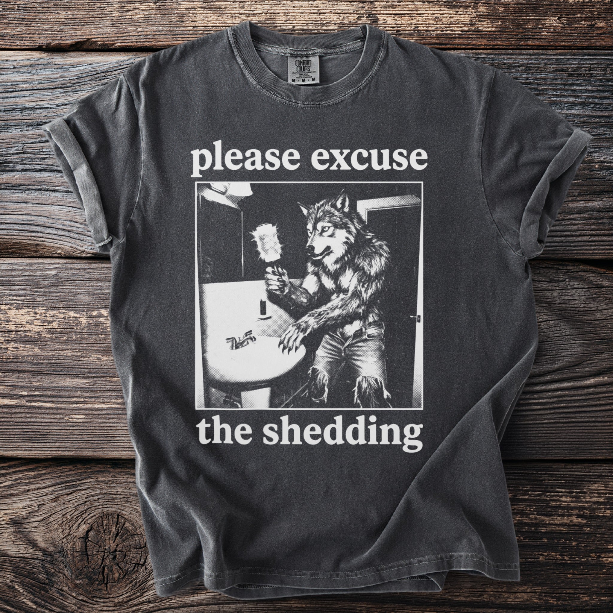 Dark grey t-shirt with a werewolf at a sink and the text "please excuse the shedding."
