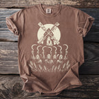 Brown t-shirt with a graphic of a windmill above skull-faced figures holding sickles in a wheat field.