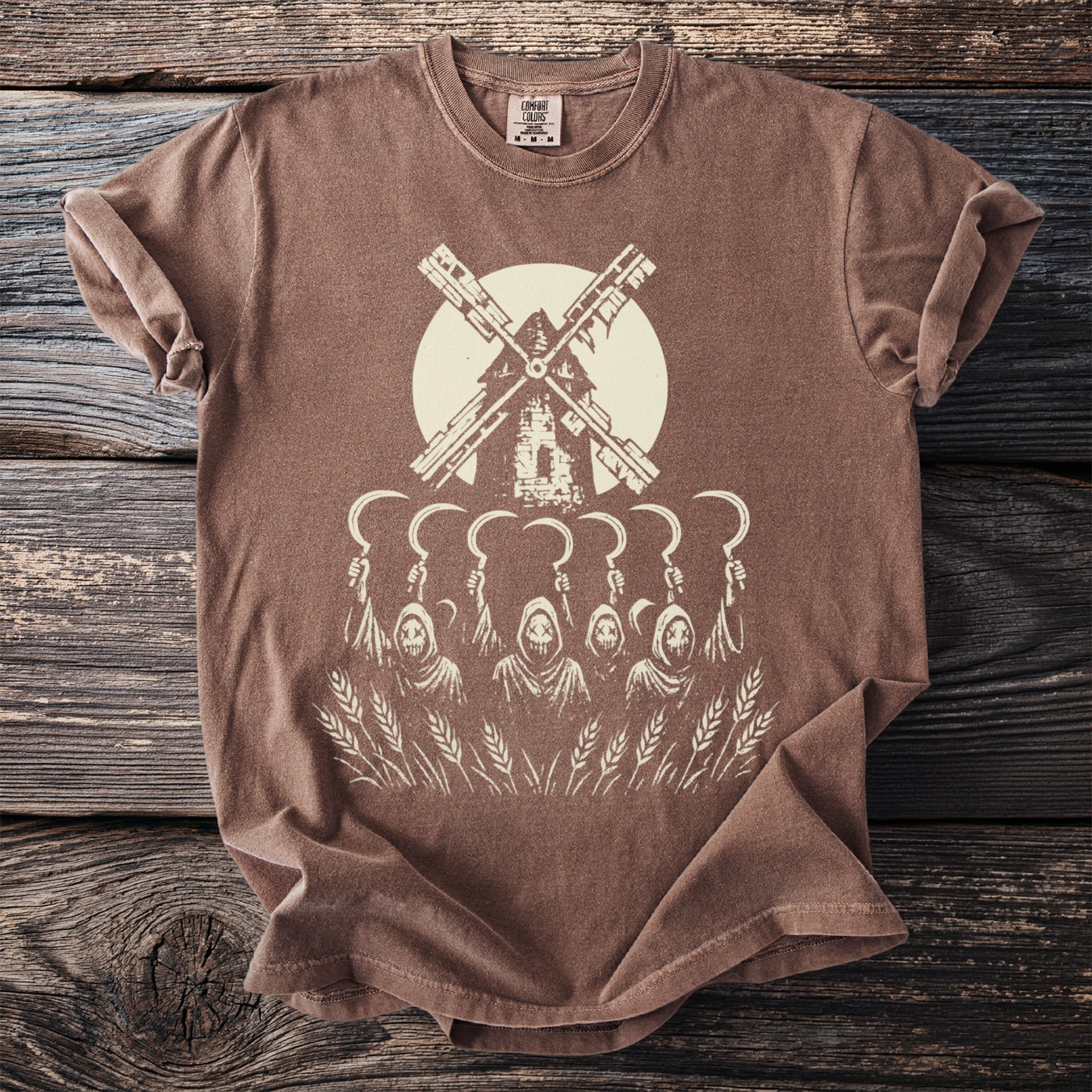 Brown t-shirt with a graphic of a windmill above skull-faced figures holding sickles in a wheat field.