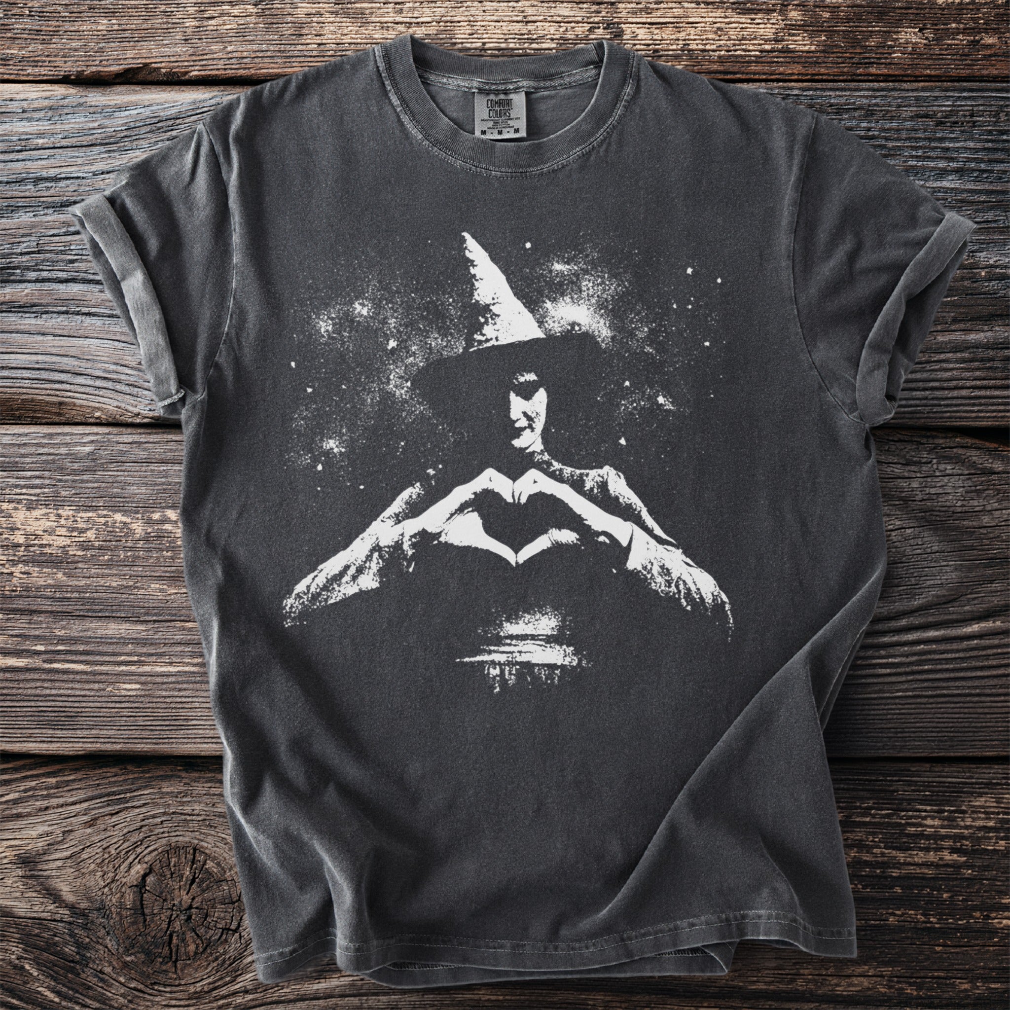 Dark grey t-shirt with white graphic of a witch making a heart shape.