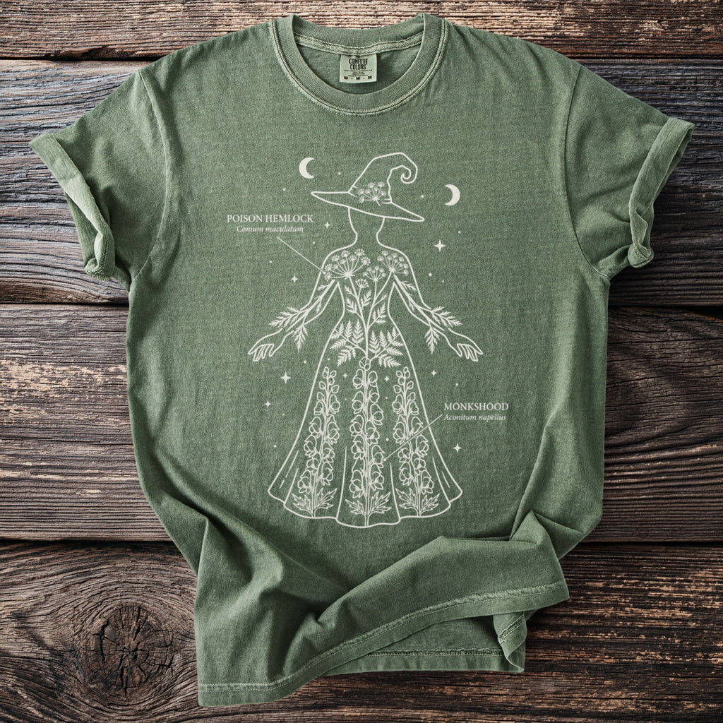 Green t-shirt with white outline drawing of a witch holding poison hemlock and monkshood.
