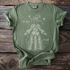 Green t-shirt with white outline drawing of a witch holding poison hemlock and monkshood.
