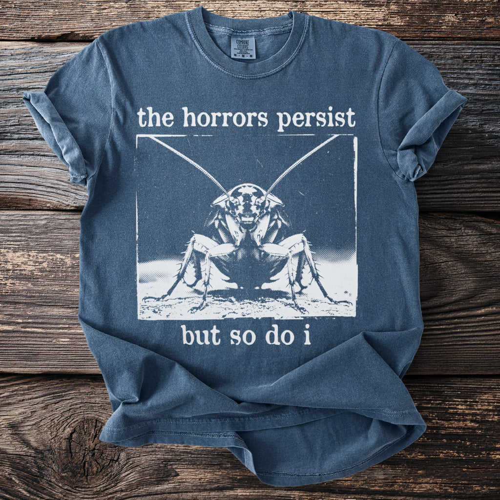 Blue t-shirt with "the horrors persist but so do i" and a cockroach graphic.