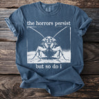 Blue t-shirt with "the horrors persist but so do i" and a cockroach graphic.