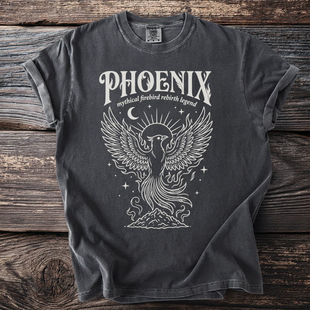 Dark grey t-shirt with white graphic of a phoenix rising from mountains, text "PHOENIX mythical firebird rebirth legend".
