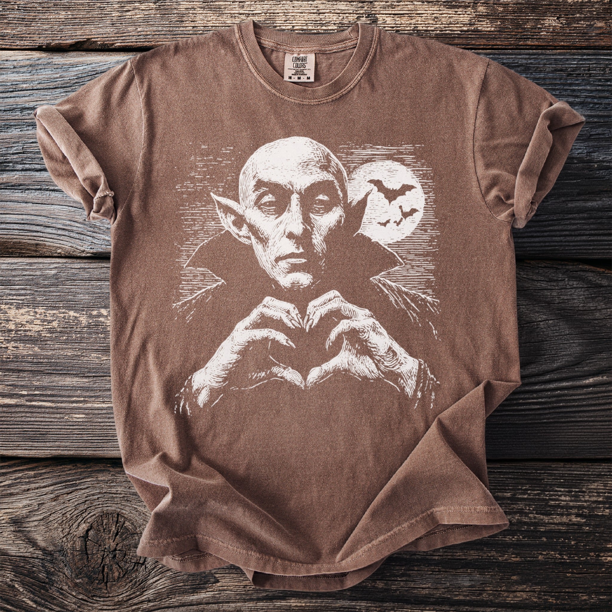 Brown t-shirt with a white graphic of a vampire making a heart shape with his hands.
