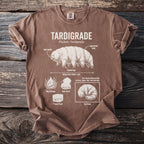 Brown t-shirt with tardigrade illustration and its characteristics labeled: segmented body, tube mouth, clawed legs.
