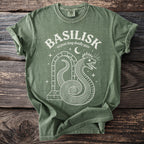 Green t-shirt with white graphic of a coiled basilisk snake and moon.