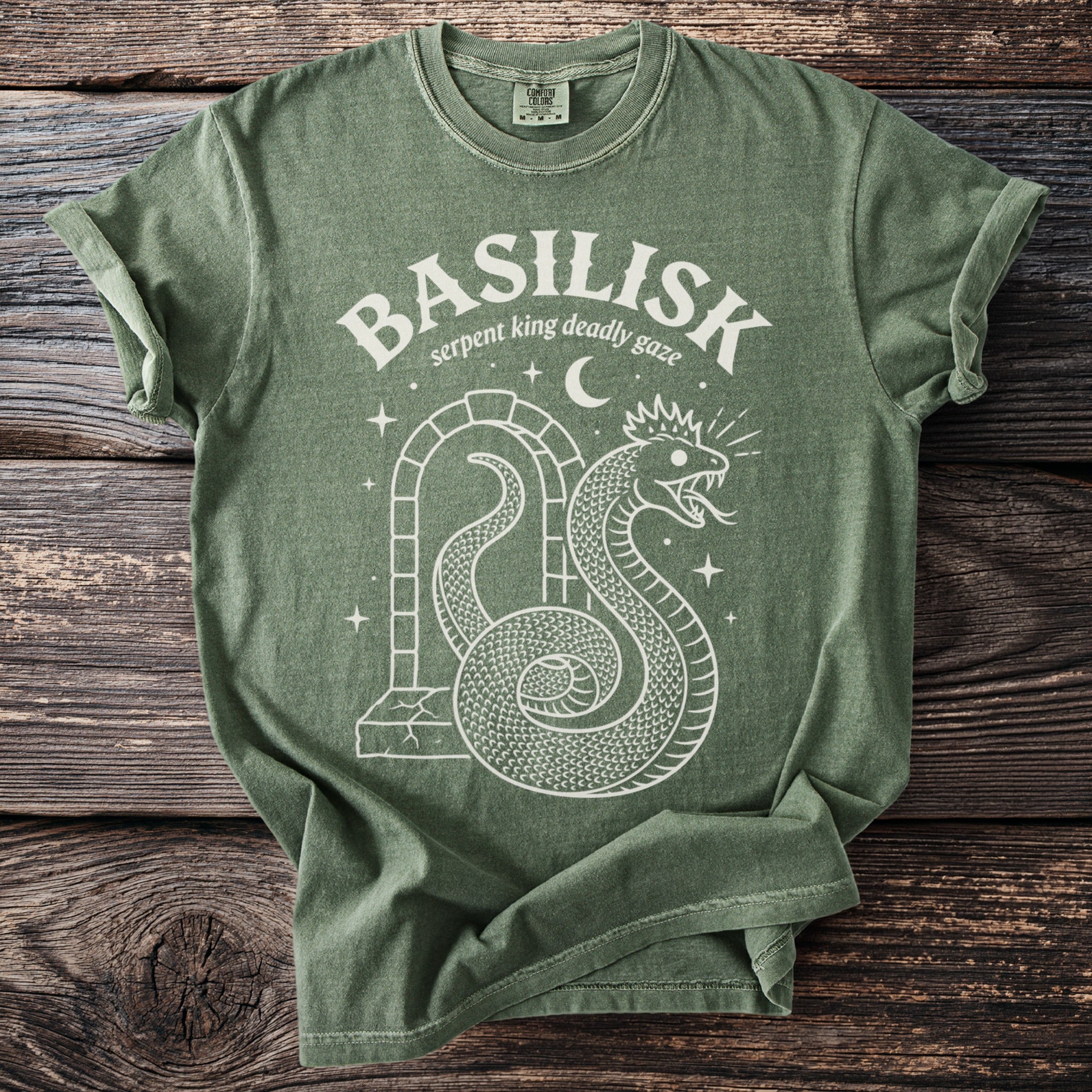 Green t-shirt with white graphic of a coiled basilisk snake and moon.