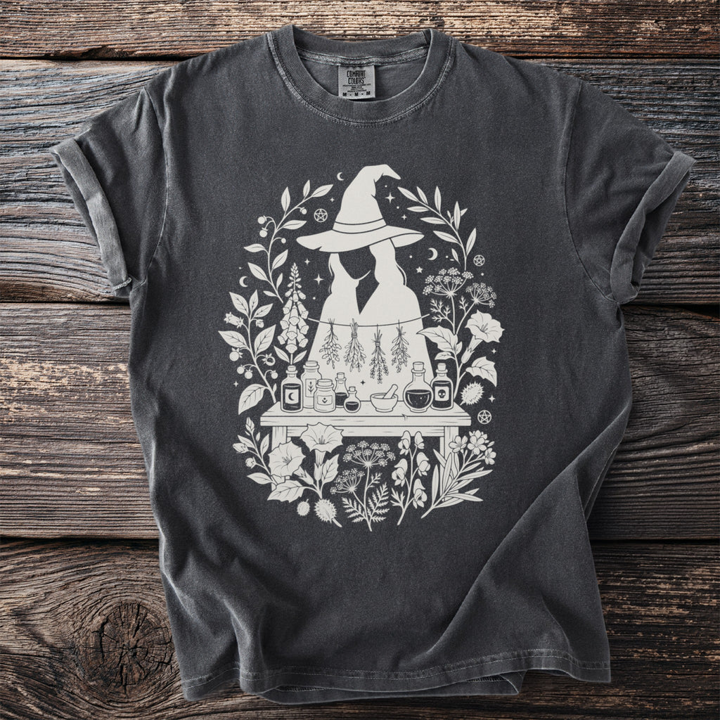 Dark gray t-shirt with white witchy floral design and potion bottles.