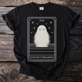 Black t-shirt featuring a tarot card with a ghost, stars, and text "DEAD BUT DREAMING".