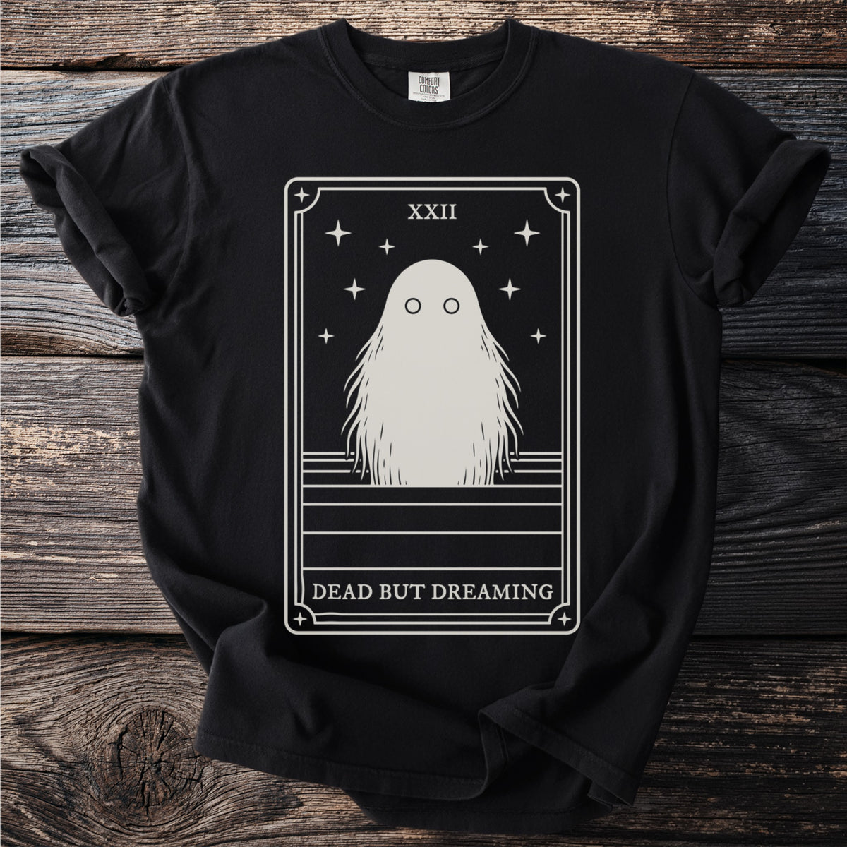 Black t-shirt featuring a tarot card with a ghost, stars, and text "DEAD BUT DREAMING".