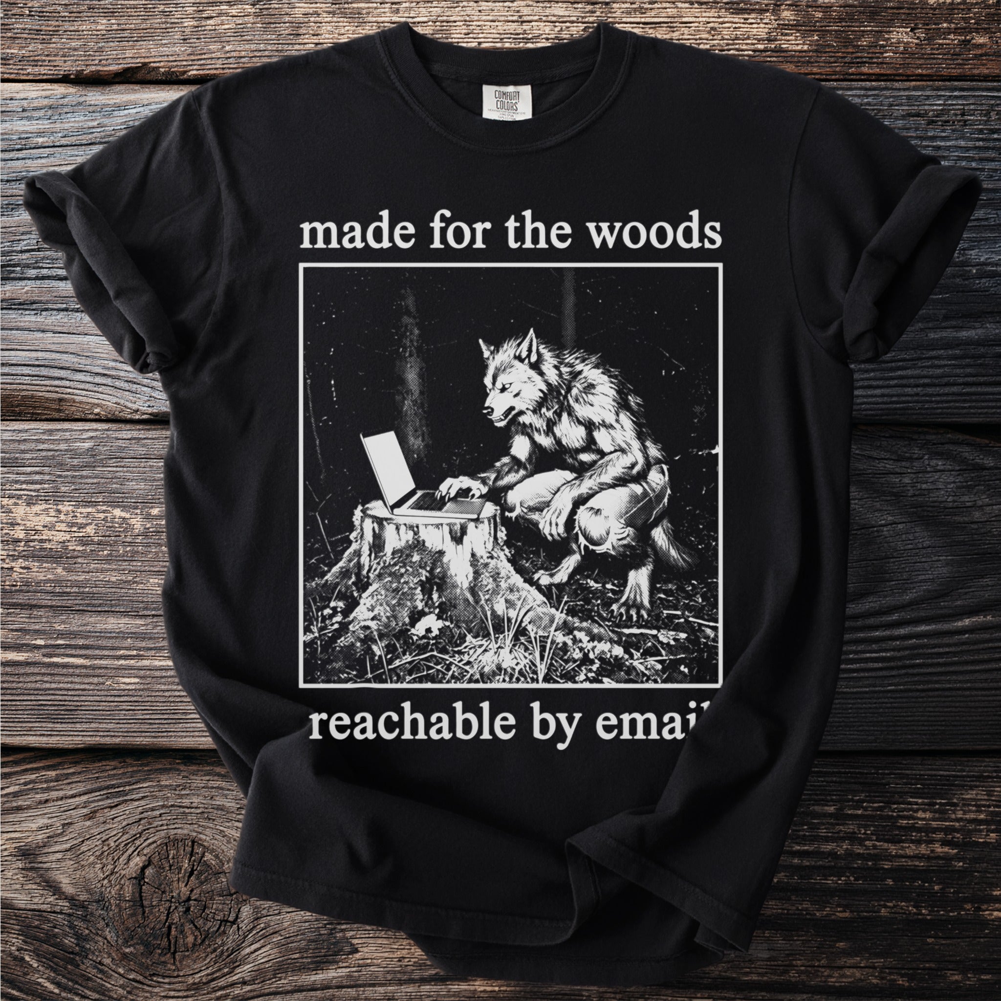 Black t-shirt with werewolf using a laptop on a tree stump, "made for the woods" and "reachable by email".