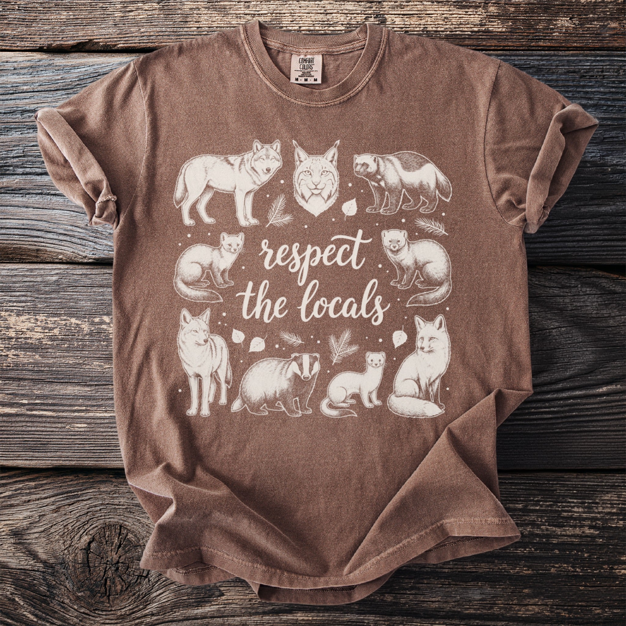 Brown t-shirt with white line art of various woodland animals and text "respect the locals".