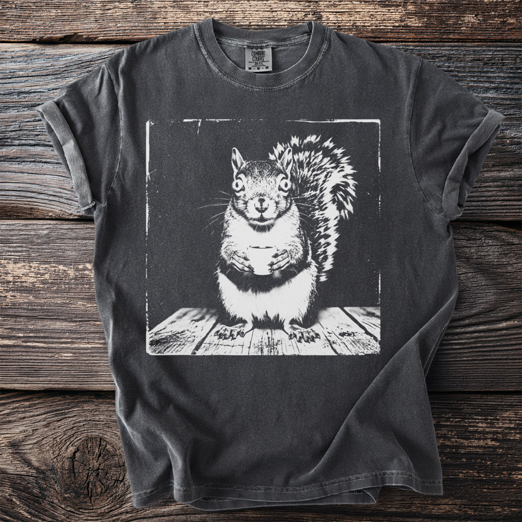 Dark grey t-shirt with a white graphic of a squirrel holding a cup on a wooden surface.