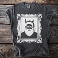 Dark t-shirt with distressed graphic of a devilish Santa Claus in an ornate frame.