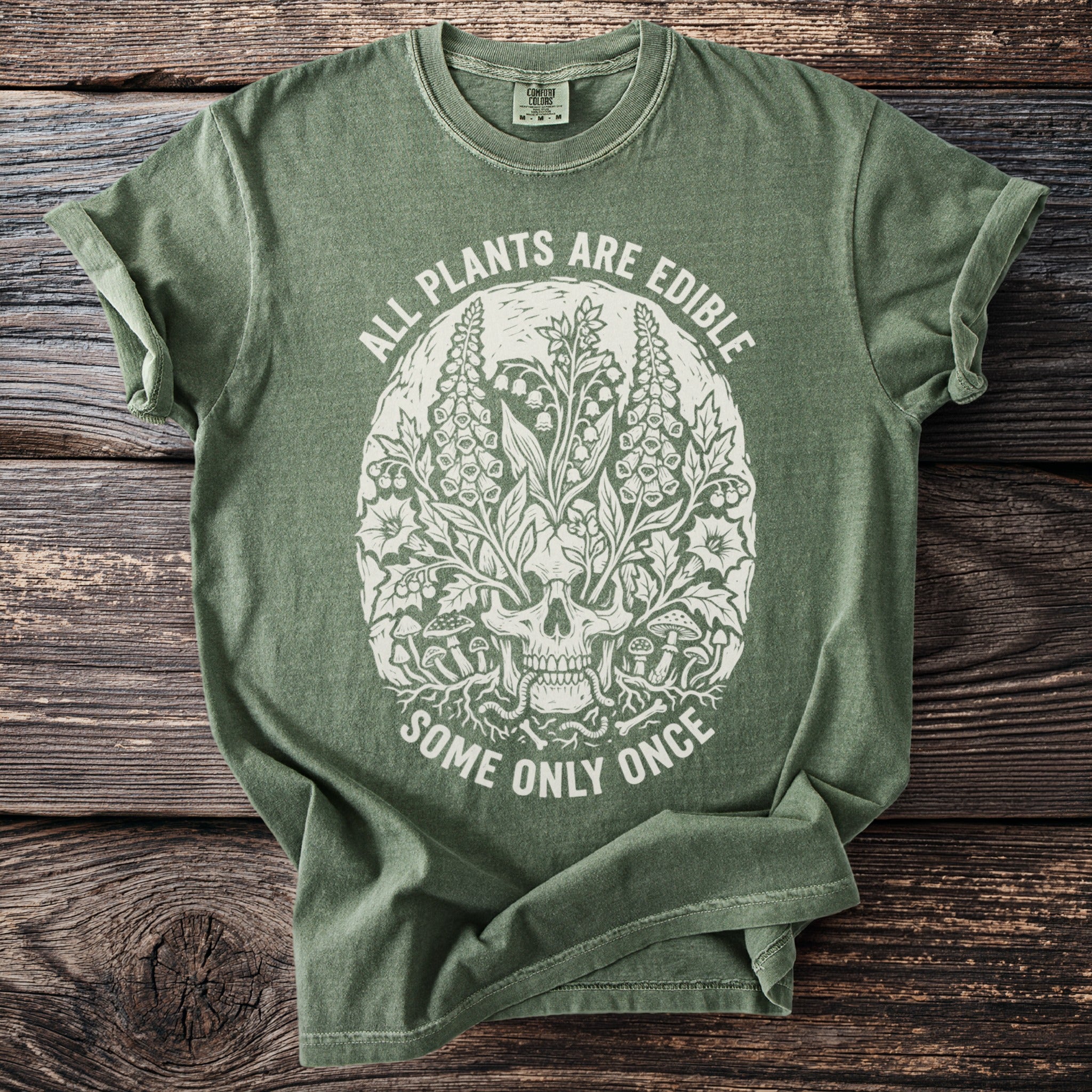 Green t-shirt with skull and botanical graphic, text "ALL PLANTS ARE EDIBLE SOME ONLY ONCE".