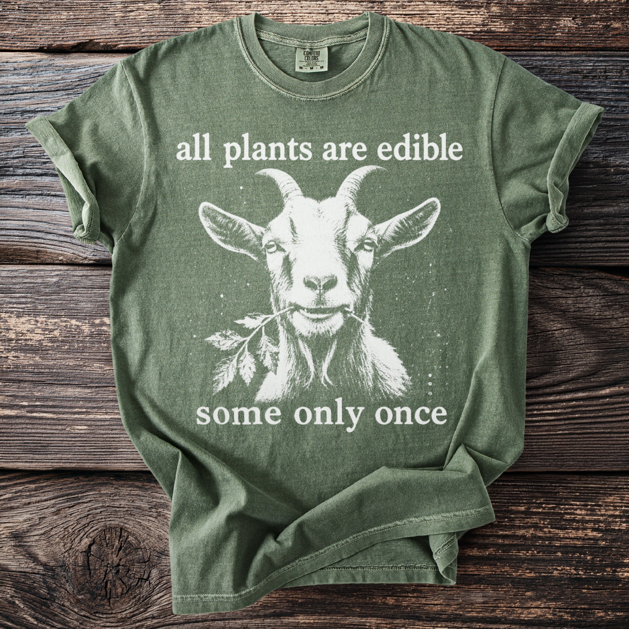 Green t-shirt with white graphic and text: "all plants are edible" and "some only once".
