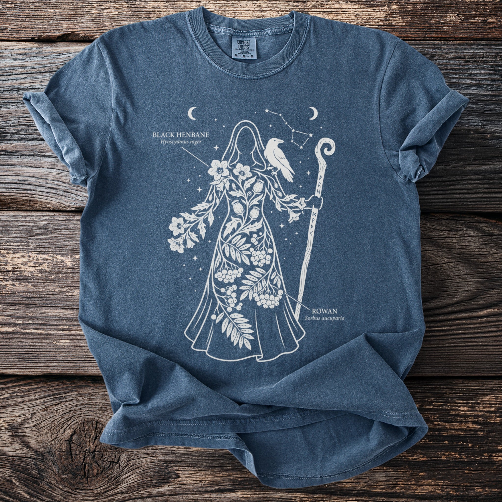 Blue t-shirt featuring a white constellation figure with plants, a bird, and text.