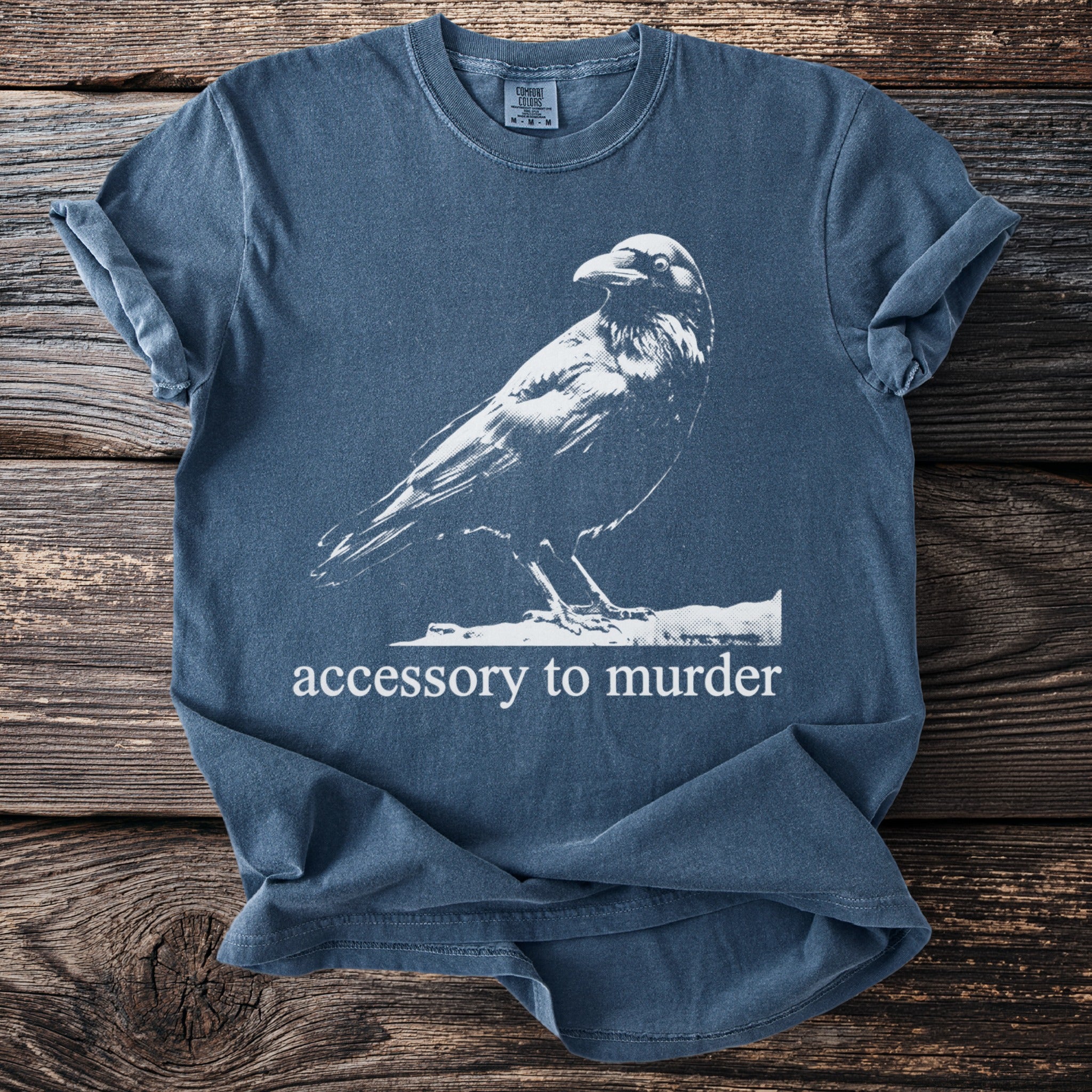 Blue t-shirt with white crow graphic and text "accessory to murder".