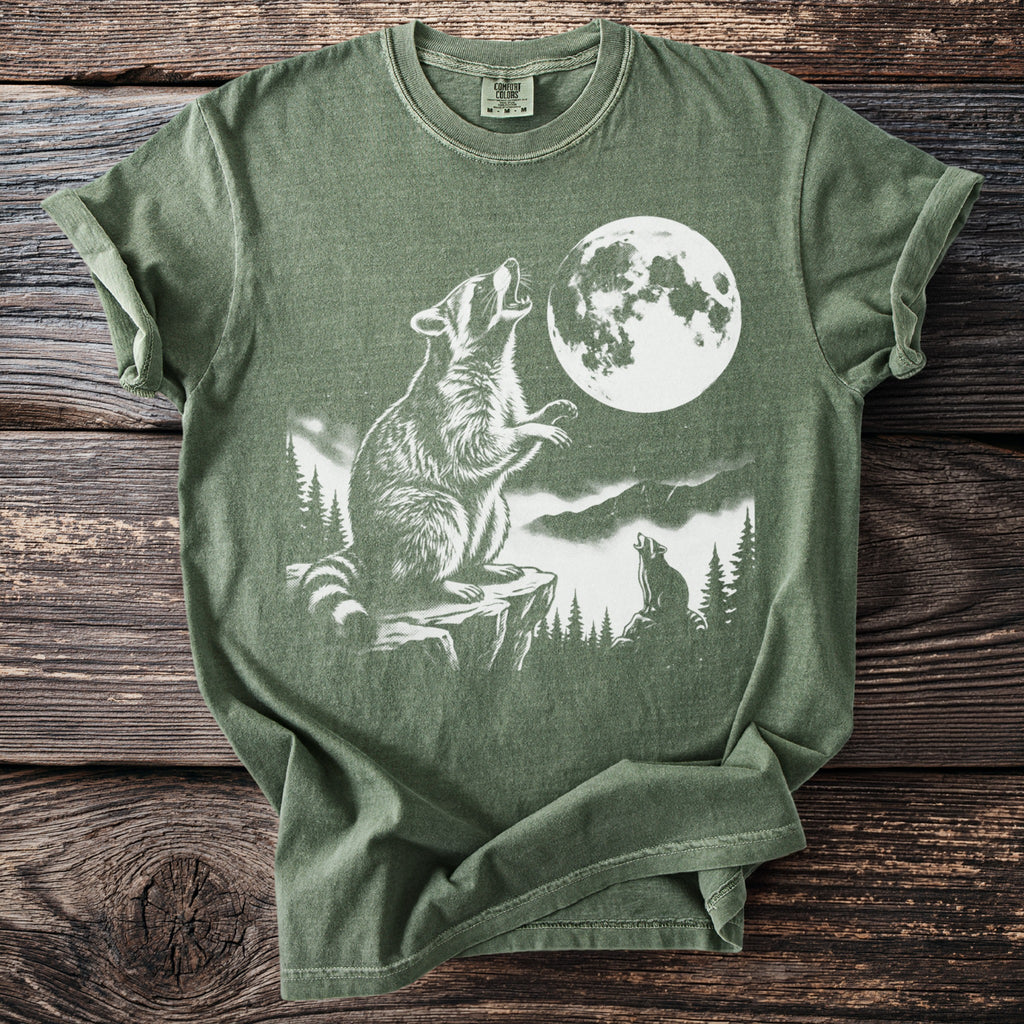 Green t-shirt with a white graphic of raccoons howling at the moon.