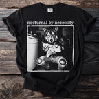 Black t-shirt with "nocturnal by necessity" and wolf holding kitten graphic.