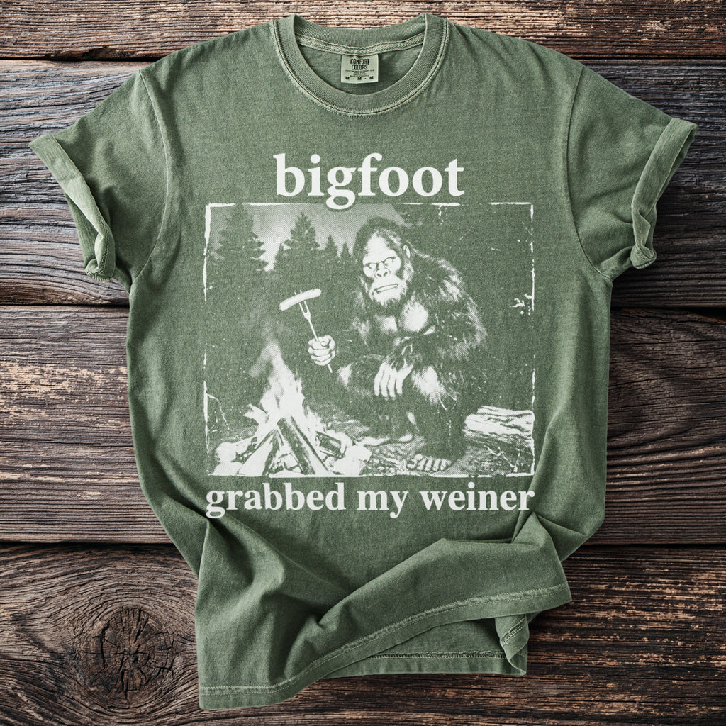 Green t-shirt with Bigfoot by campfire, text says bigfoot grabbed my weiner.