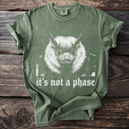 Green t-shirt with a grayscale bat print and white text that reads "it's not a phase."