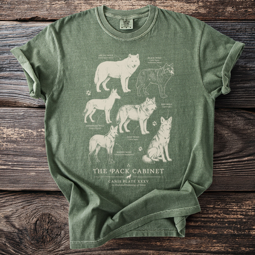 Green t-shirt with illustration of six wolf species and "The Pack Cabinet" text.