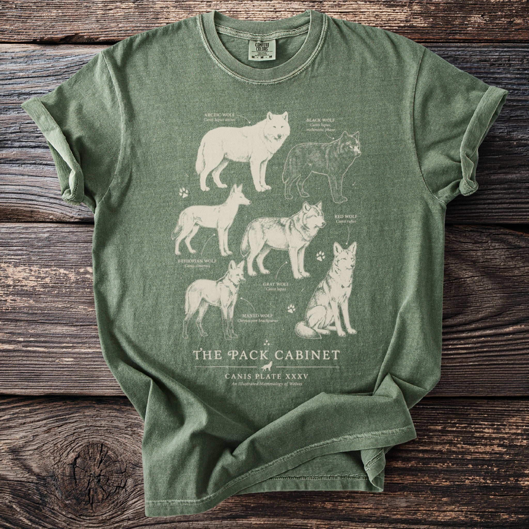 Green t-shirt with illustration of six wolf species and "The Pack Cabinet" text.