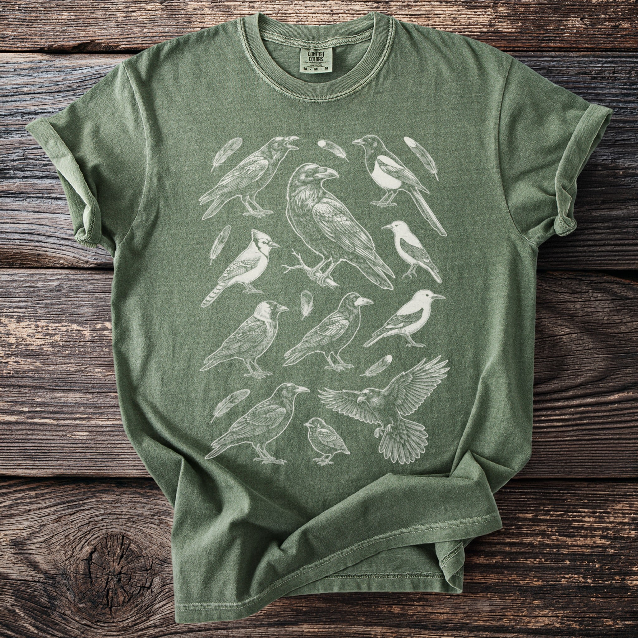 Green t-shirt with a white line drawing of various birds and feathers.