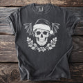 Dark t-shirt with white skull wearing Santa hat, bat wings, and holly wreath.