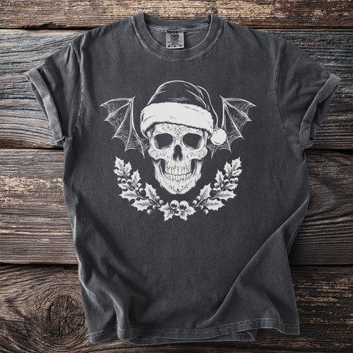 Dark t-shirt with white skull wearing Santa hat, bat wings, and holly wreath.