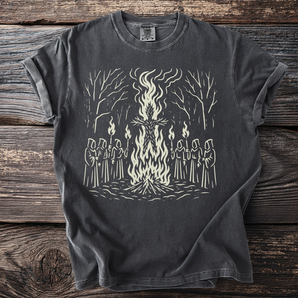 T-shirt with a graphic of robed figures holding torches around a bonfire with a straw figure.