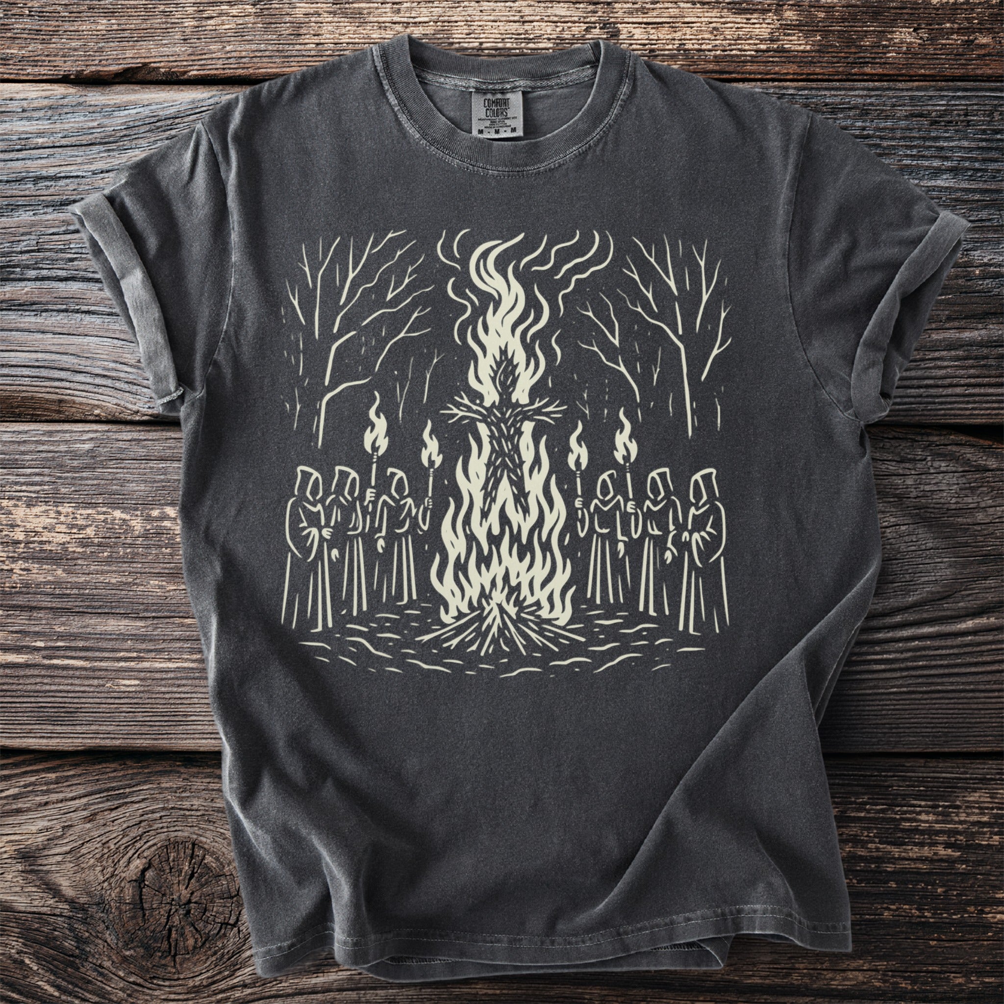 T-shirt with a graphic of robed figures holding torches around a bonfire with a straw figure.
