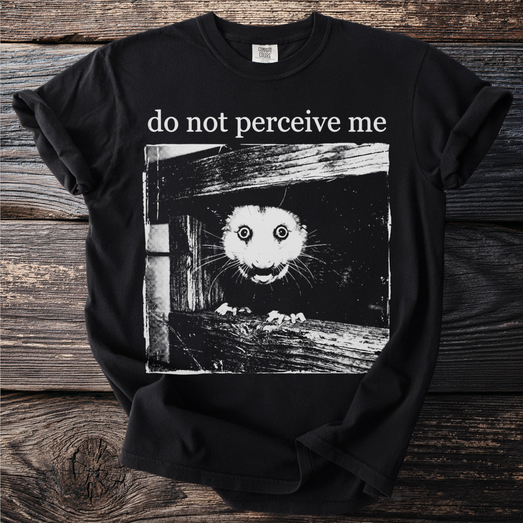 Black T shirt with a bushbaby peering through wooden planks and “do not perceive me” text.