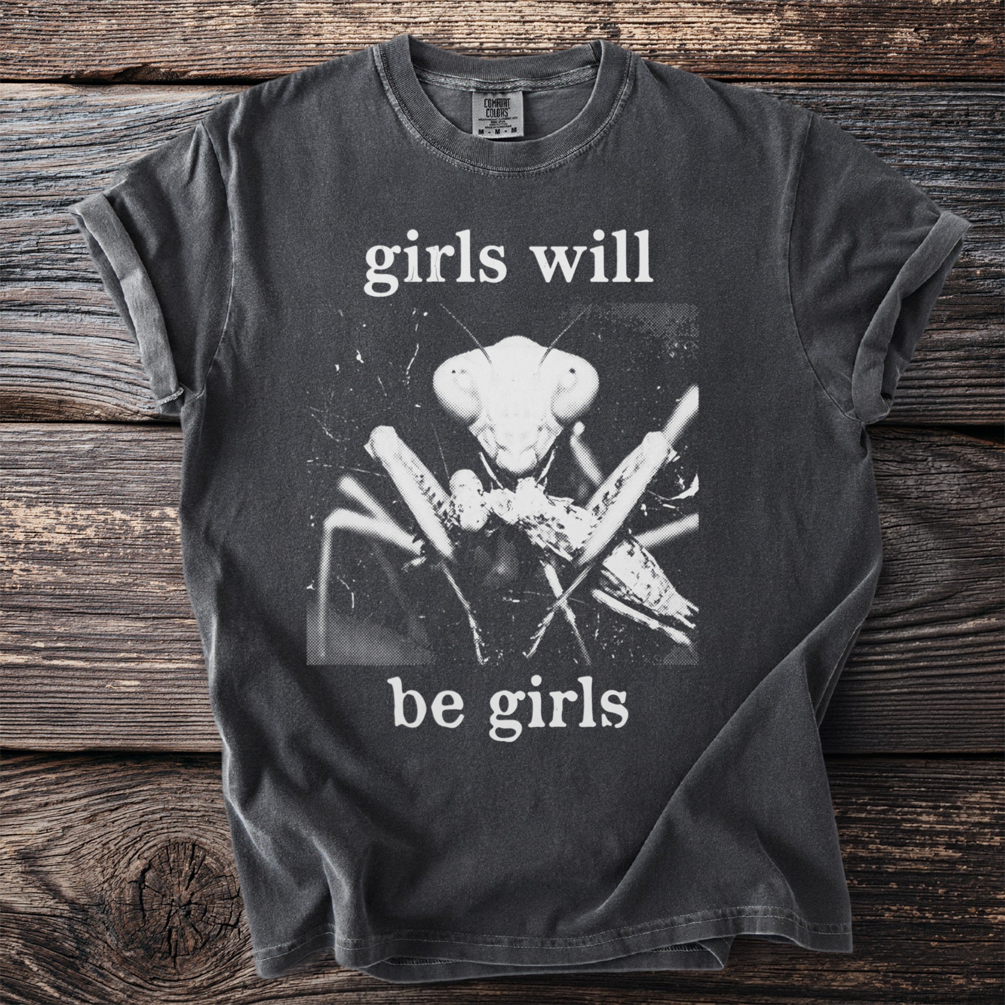 Dark grey t-shirt with a praying mantis graphic and text "girls will be girls".