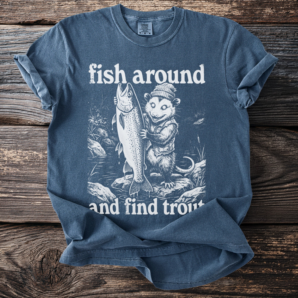 Blue t-shirt graphic with opossum holding large trout, text "fish around and find trout".