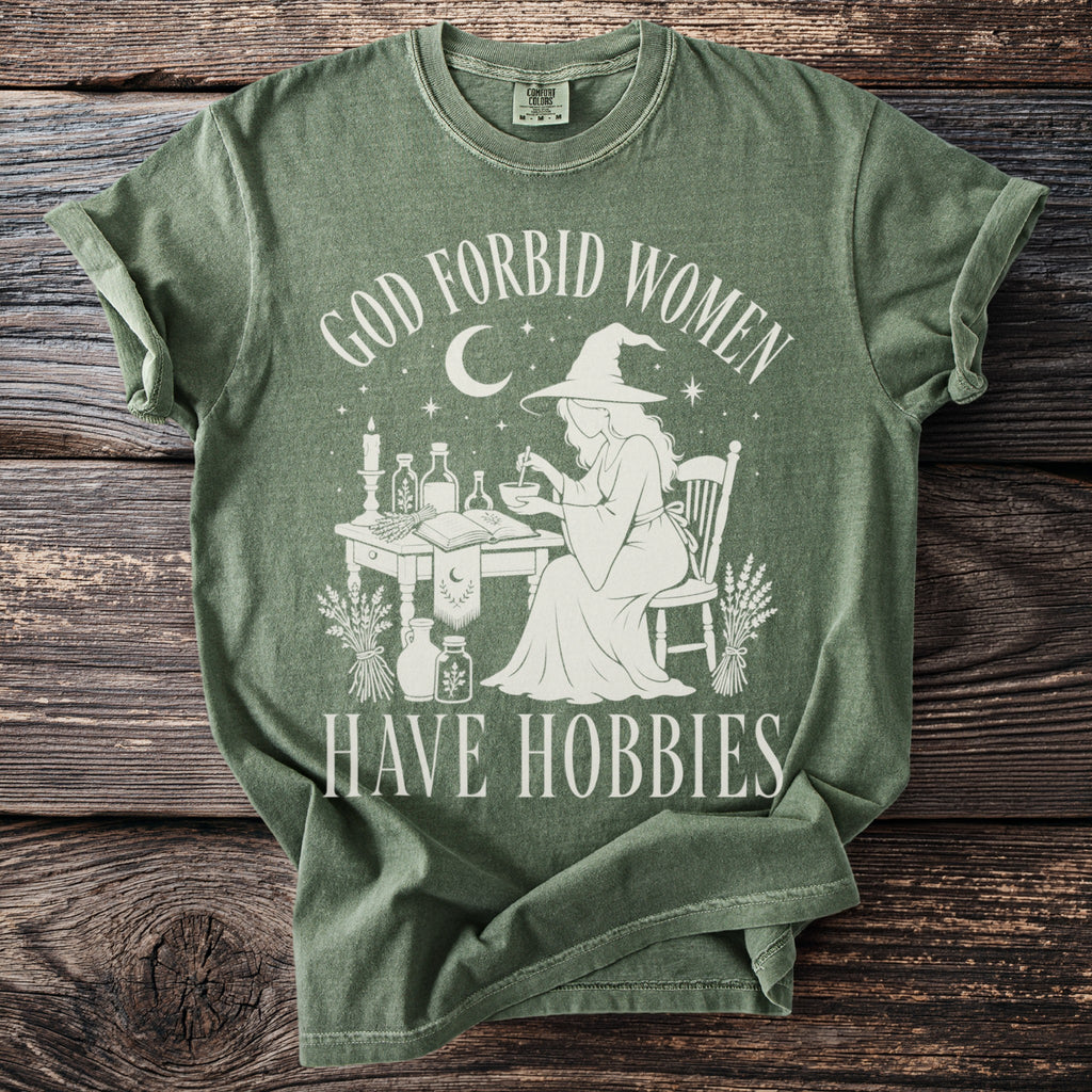 Green t-shirt with "God forbid women have hobbies" text and witch graphic.
