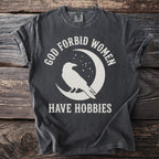 Gray t-shirt with white text and crow graphic on moon: "GOD FORBID WOMEN HAVE HOBBIES"