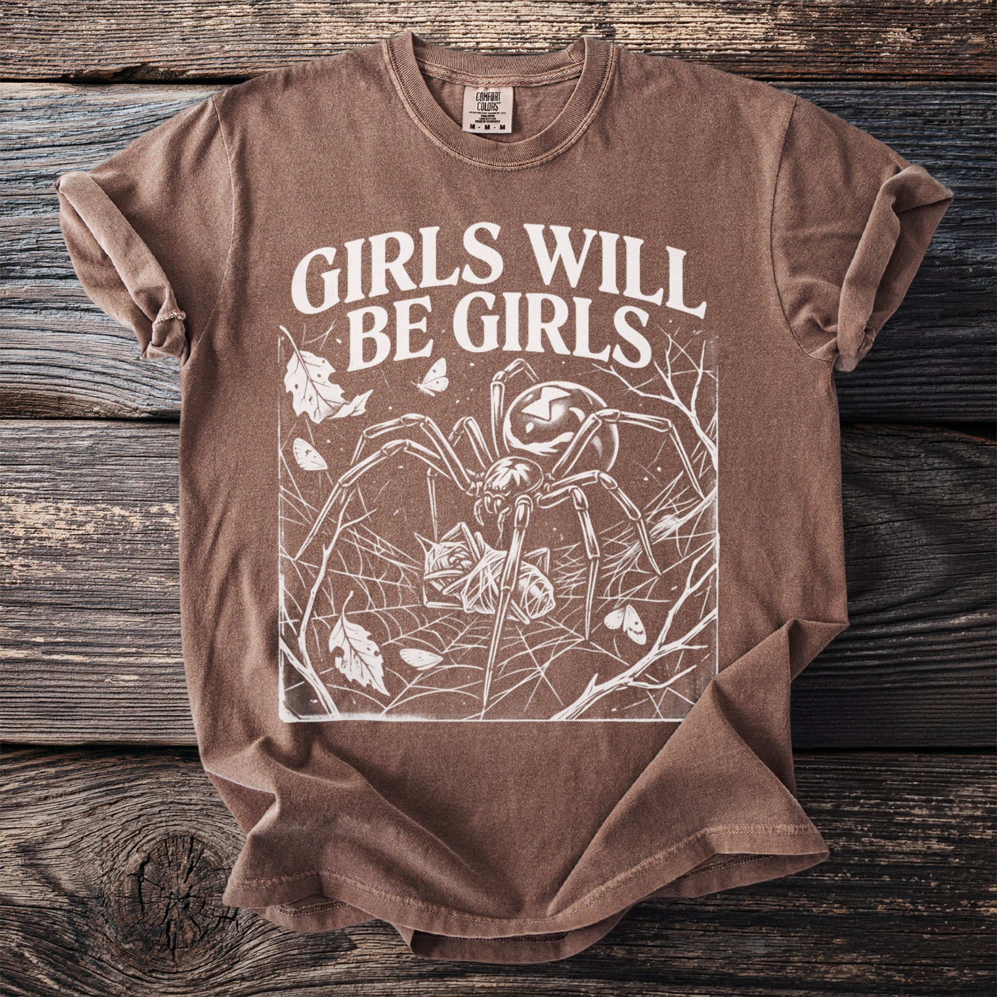 Brown t-shirt with "Girls Will Be Girls" text and spider graphic.