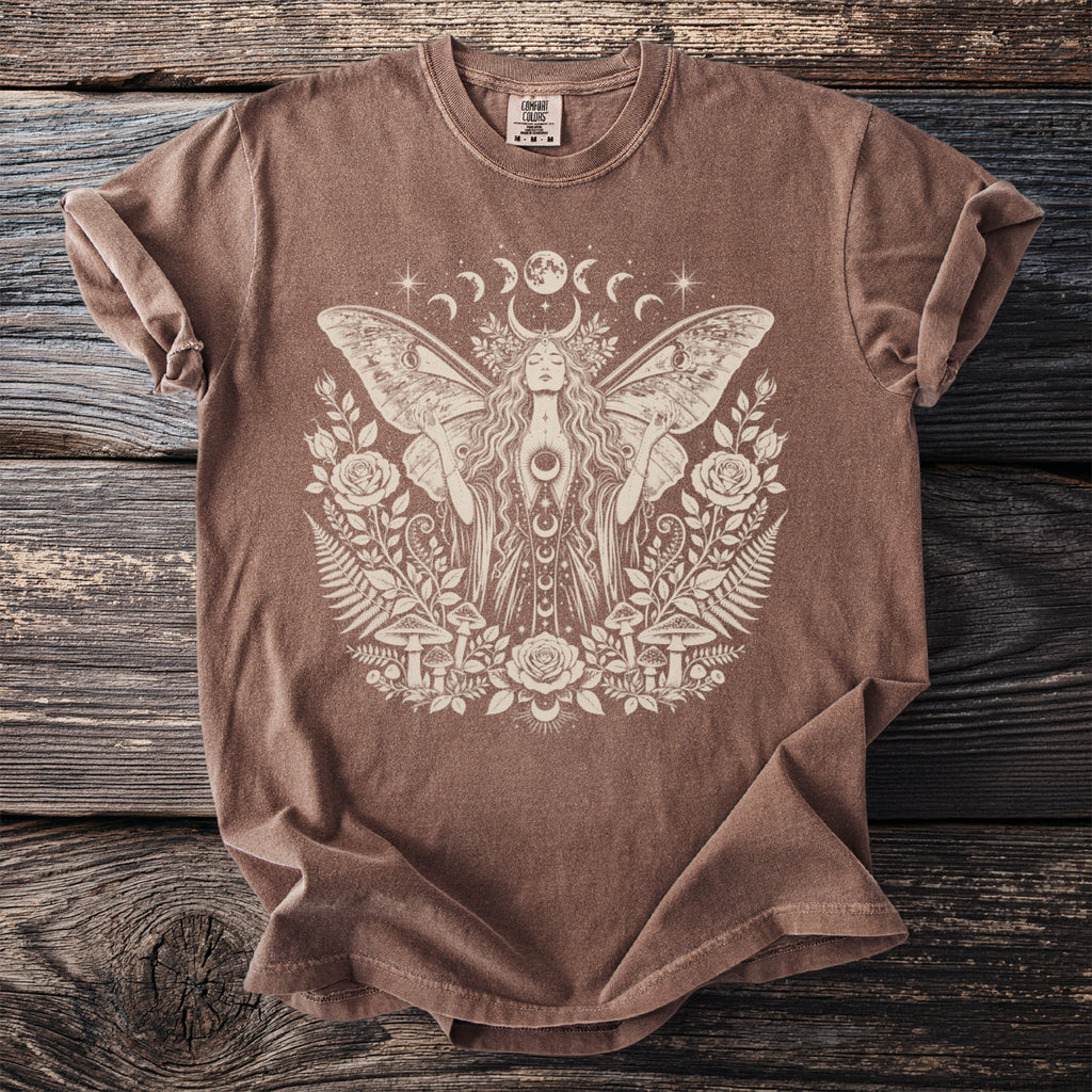 Brown t-shirt with a celestial moth woman graphic surrounded by flora and mushrooms.