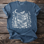 Dark blue t-shirt with white graphic of stacked books, moon, candle, moth, and key.