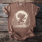 Brown t-shirt with a Krampus graphic carrying a sack and branches under the moon.