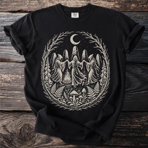 Black t-shirt with a circular graphic of cloaked figures dancing around a bonfire.