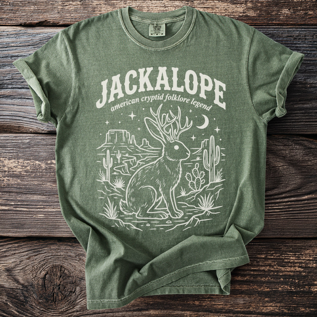 Green t-shirt featuring a white line drawing of a jackalope and desert landscape with text.