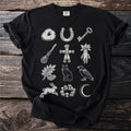 Black t-shirt with mystical illustrations of a donut, horseshoe, key, broom, doll, mandrake, berries, cat, raven, rabbit, mushrooms, and moon.