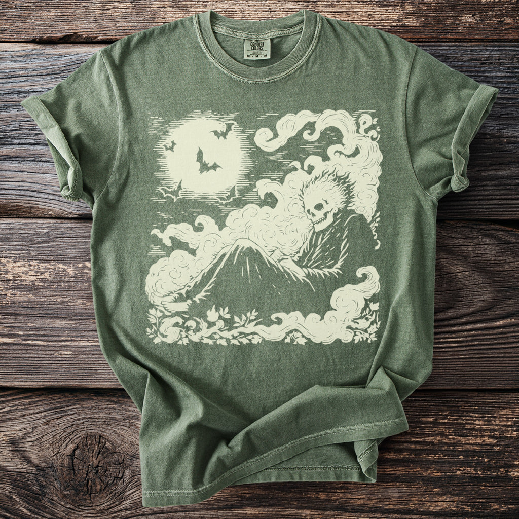 Green t-shirt with a cream-colored graphic of a skeleton sitting in clouds under a full moon.